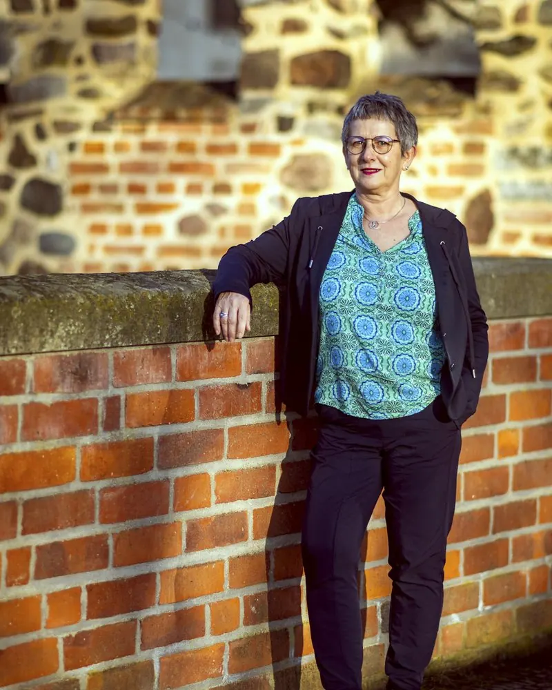 Businessportrait einer Selbstständigen im Abendlicht an einer Backsteinmauer