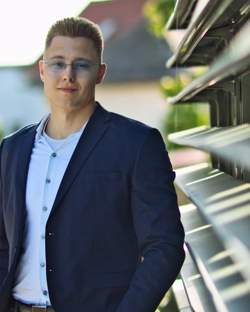 Businessportrait eines Mannes im Sakko, angelehnt an eine Metallfassade